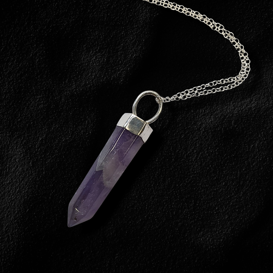 A sterling silver chain necklace featuring a polished purple amethyst crystal point pendant with a silver cap, laying on black sand.
Wilde Folk Jewellery is inspired by nature, folklore & mysticism. A queer-owned brand using responsibly sourced gemstones & recycled precious metals.