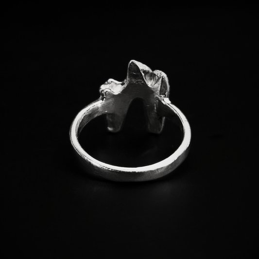 A chunky, luxury, solid silver ring made using the casting of a real fox tooth, sits against the black background. It has been photographed from the back to show that the inside of the ring is completely smooth for a comfortable wear. The pale silver ring is in an alternative, heavy metal style for fans curios, oddities, taxidermy and skeletons.
