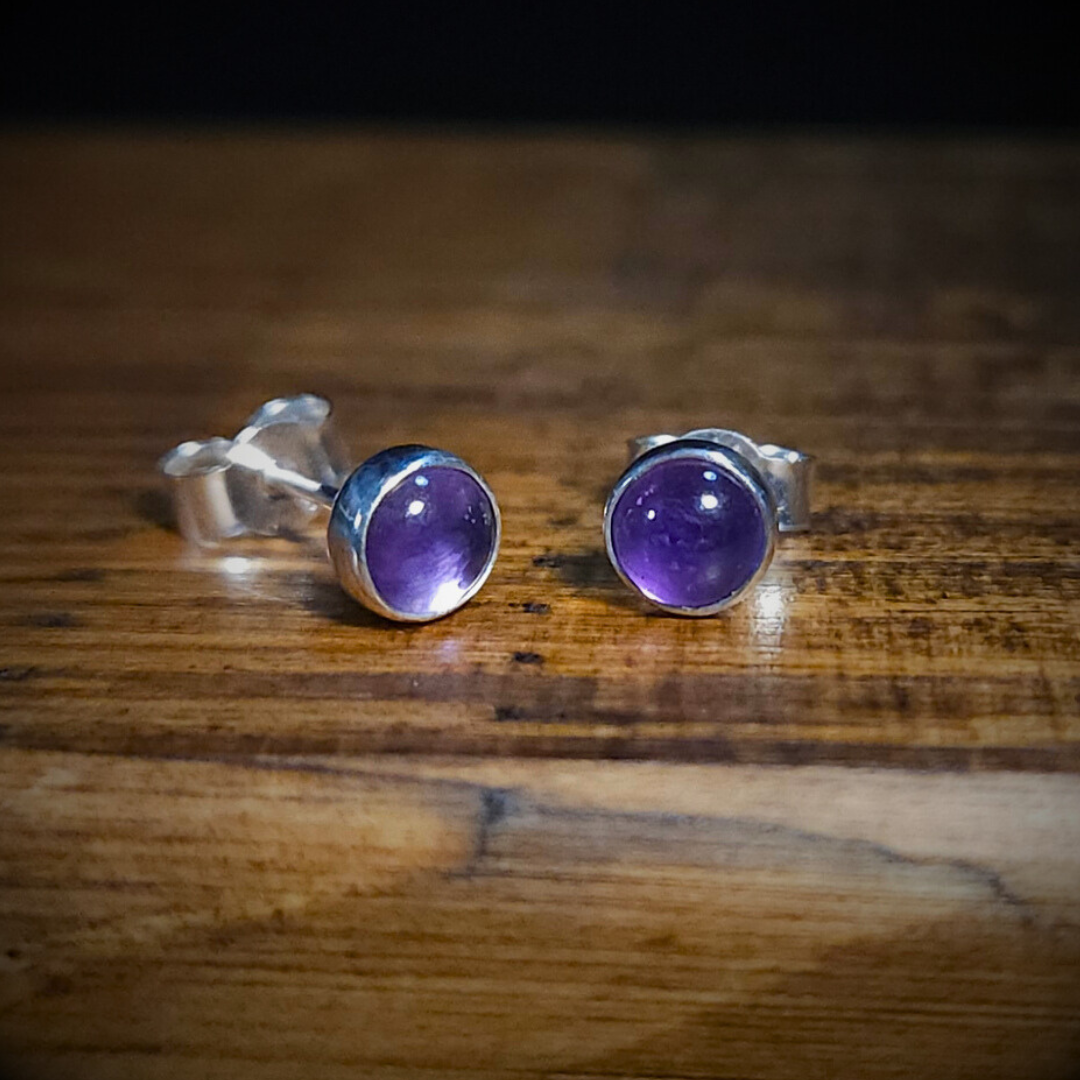 Round sterling silver & amethyst stud earrings on a wooden surface