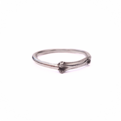 A silver ring sits against a plain white background. Part of the band of the ring is the solid silver casting of a little bone. The details are oxidised to show all the beautiful natural texture.