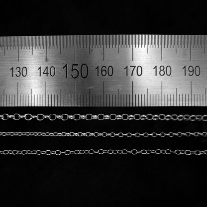 Three different types of chain are laid out against a black background with a ruler above them.
They are laid from thickest at the top to thinnest at the bottom demonstrate the difference in link size and thickness.