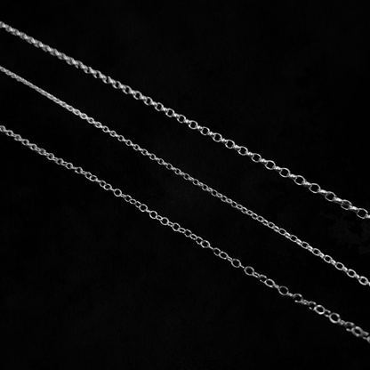 Three different types of chain are laid out against a black background.
They are laid from thickest at the top to thinnest at the bottom demonstrate the difference in link size and thickness.