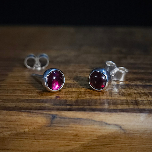 Sterling silver & garnet stud earrings on a wooden surface
