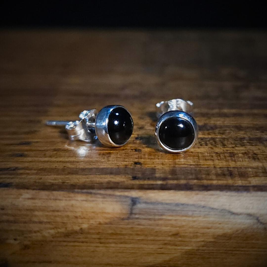 Pair of sterling silver & black onyx earrings on a wooden surface