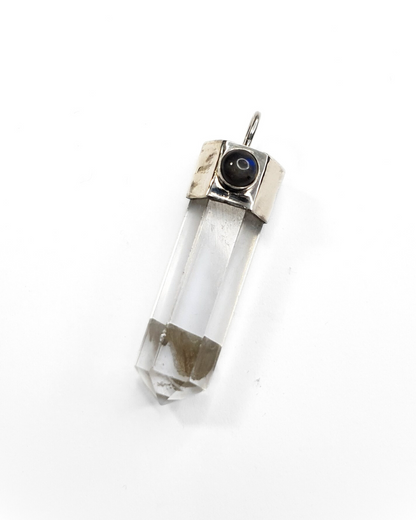 A clear quartz crystal point pendant with a sterling silver setting, adorned with a small labradorite stone, displayed against a white background.