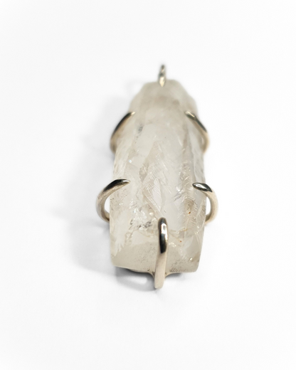A rough-cut, semi-transparent, rectangular quartz pendant is photographed on a white background. The rough, beautifully textured stone is set in 6 silver claws - 1 and the top and bottom and two on each side. 