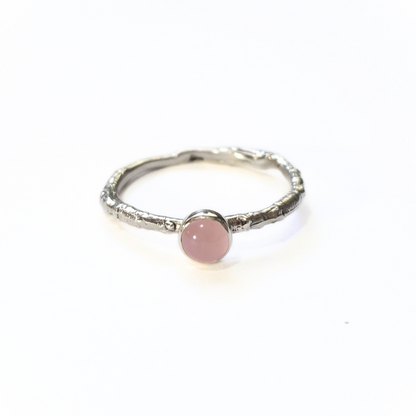 Silver ring with a 5mm rose quartz gemstone on a plain white. The band is made from the casting of a real twig so it is full of bark texture. The rose quartz has a gentle light pink blush.