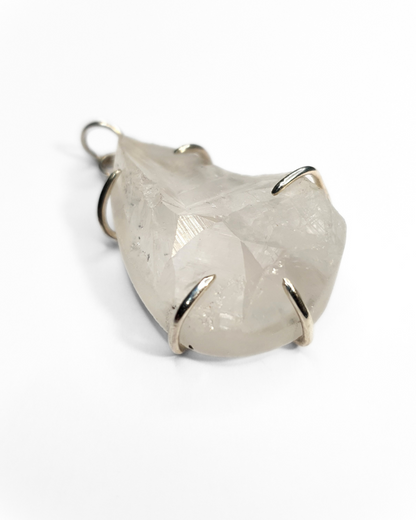 A rough-cut, teardrop-shaped quartz pendant is photographed on a white background. The rough, beautifully textured stone is set in 5 evenly spaced silver claws . A silver jump ring is visible at the top.