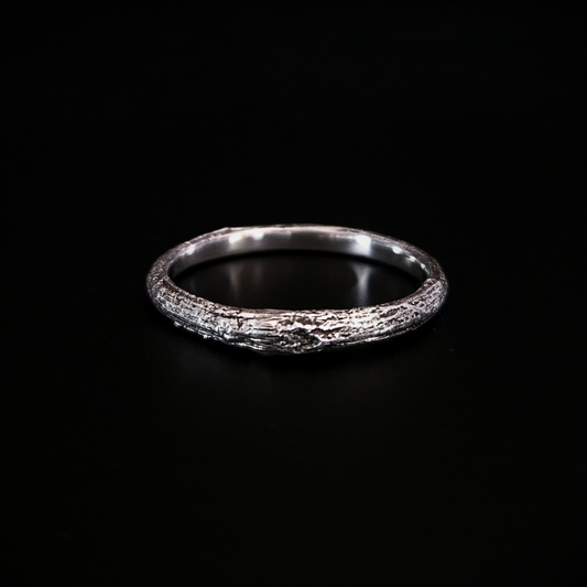 A wood-textured sterling silver band ring shown on a solid black background. The recesses have been oxidised black to reveal the gorgeous oak bark casting on the surface and the inside of the band is completely smooth for comfort.