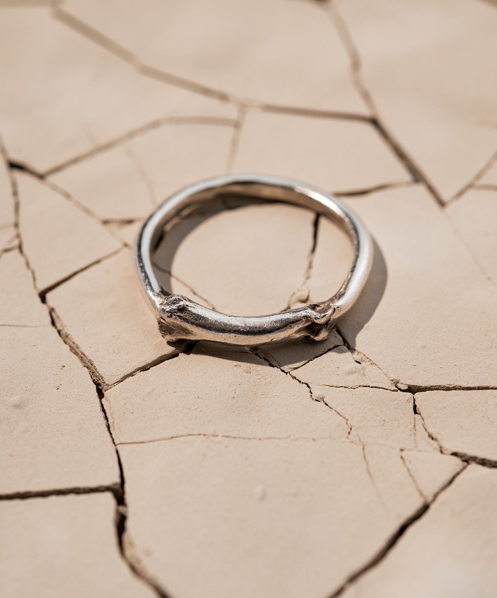 Sterling silver Bone Ring Laying on Cracked Desert Earth