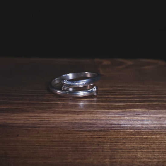A stop motion style video shows an open bone ring in sterling silver. It is rotating to show the ring from all angles.