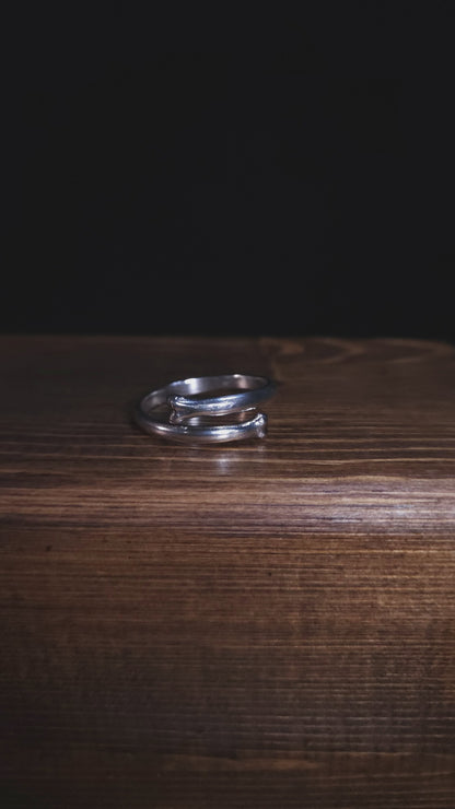 A stop motion style video shows an open bone ring in sterling silver. It is rotating to show the ring from all angles.
